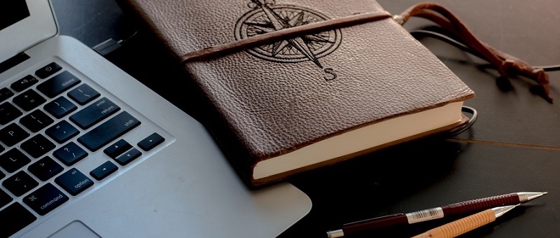 Photo of a journal, a laptop, and pencils sitting on a desk