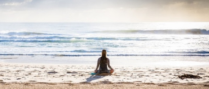 Photo of a person meditating on a quiet beach